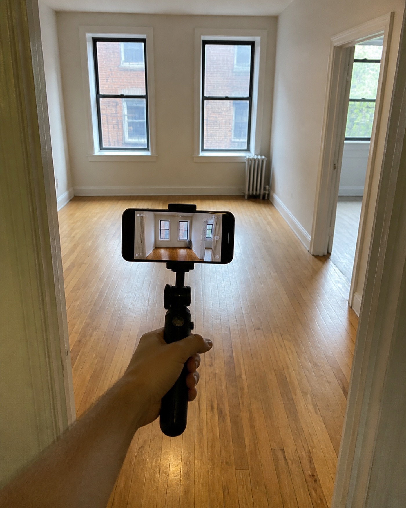 A local apartment viewer recording an unfurnished NYC rental with a smartphone